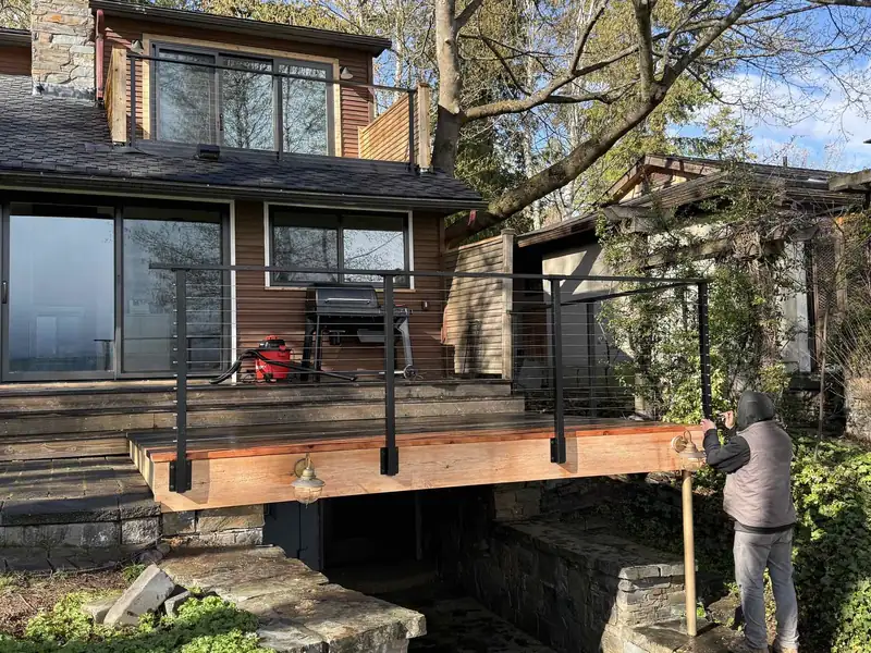 Finished deck extension with steel cable railing overlooking a lake