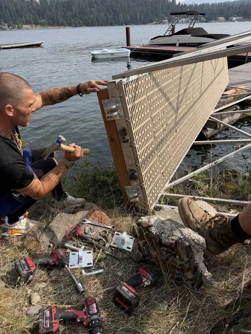 7B Handyman crew member replacing a panel of synthetic dock decking at a lakefront dock on Lake Pend Oreille