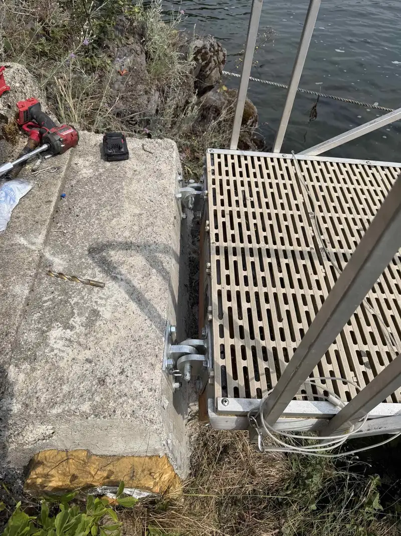 Close-up of dock mounting hardware and brackets being repaired at the shoreline