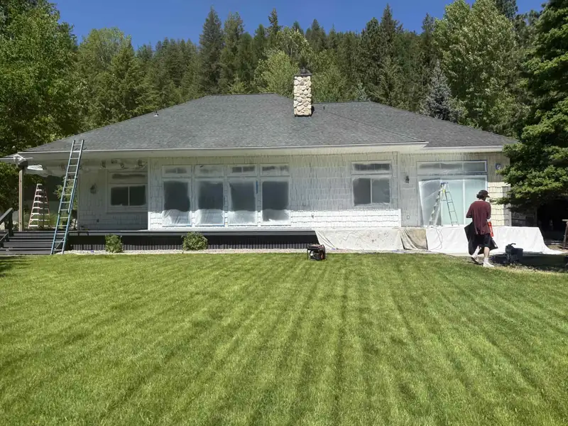 House exterior with windows masked in plastic sheeting, ladders in place, prepped for an exterior repaint by 7B Handyman