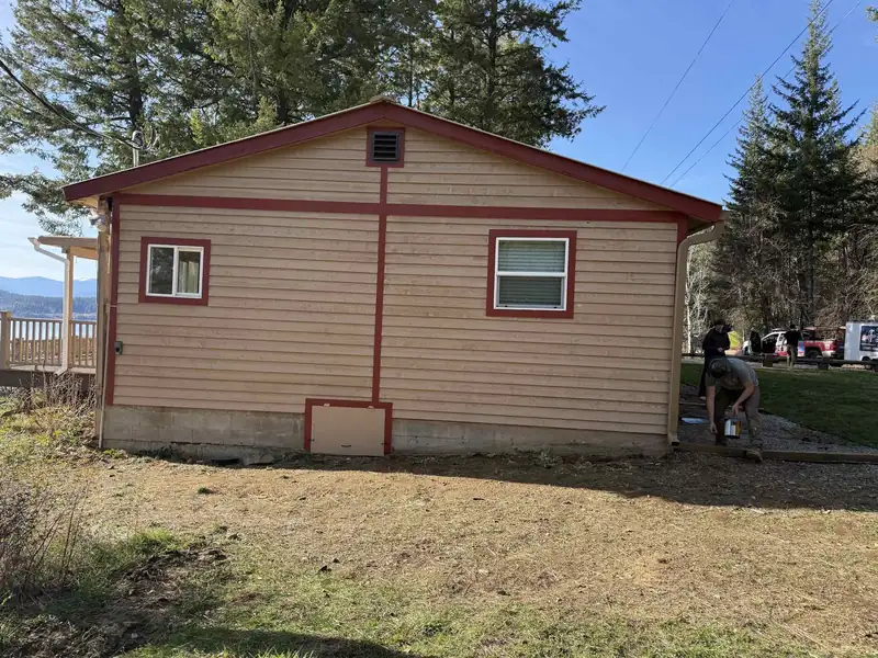7B Handyman crew painting red gable and roof trim on a metal-sided shop building