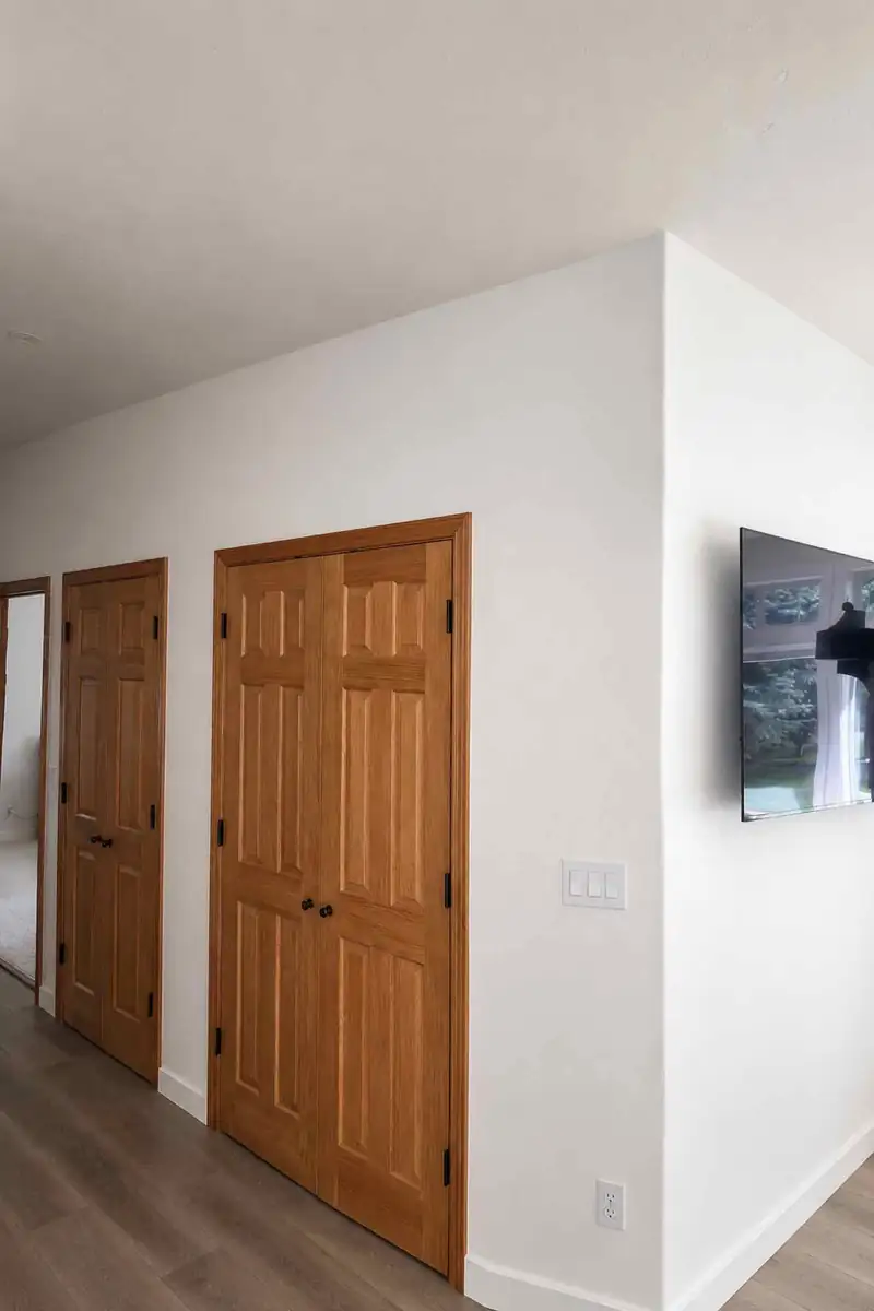 Finished interior hallway with stained wood closet doors, trim and wood-look flooring