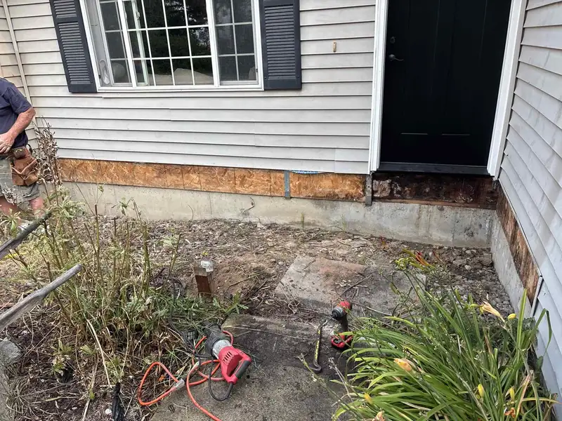 Rotted wood sill plate and OSB sheathing exposed during a siding and structural repair at a home's entry, before replacement